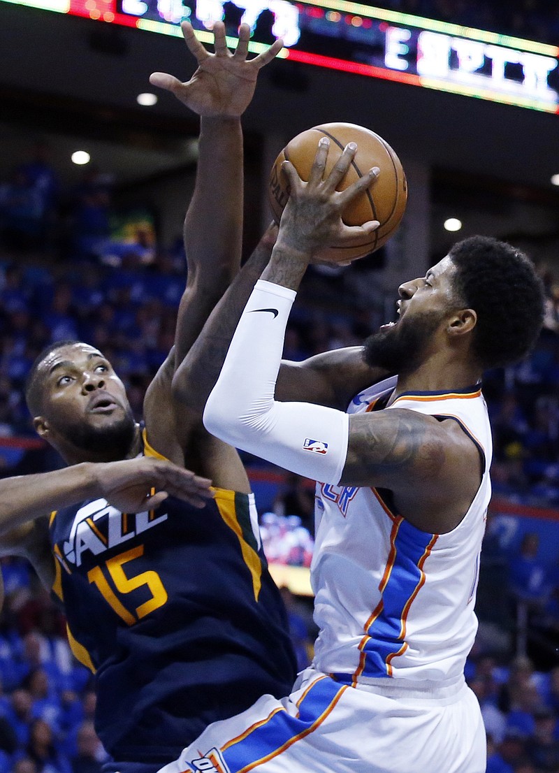 Oklahoma City Thunder forward Paul George, right, shoots as Utah Jazz forward Derrick Favors (15) defends in the first half of Game 1 of an NBA basketball first-round playoff series in Oklahoma City, Sunday, April 15, 2018. (AP Photo/Sue Ogrocki)