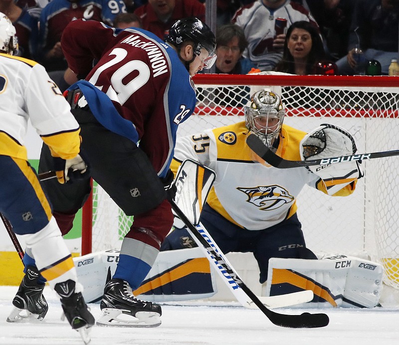 Colorado Avalanche center Nathan MacKinnon, front, fires a shot at Nashville Predators goaltender Pekka Rinne for a goal in the second period of Game 3 of an NHL hockey first-round playoff series Monday, April 16, 2018, in Denver. (AP Photo/David Zalubowski)