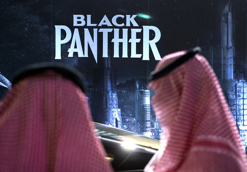 Visitors wait in front of a "Black Panther" movie banner, during an invitation-only screening, at the King Abdullah Financial District Theater, in Riyadh, Saudi Arabia, Wednesday, April 18, 2018. Saudi Arabia held a private screening of the Hollywood blockbuster "Black Panther" Wednesday, to herald the launch of movie theaters that are set to open to the public next month. (AP Photo/Amr Nabil)