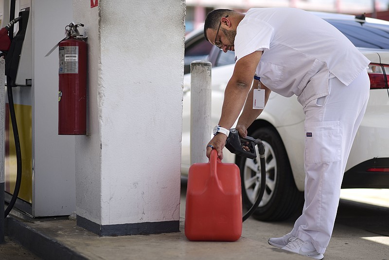 Angel Rodriguez Negron fills his gasoline container at a gas station while others line up behind him, after a general power outage in San Juan, Puerto Rico, Wednesday, April 18, 2018. Officials say it will take 24 to 36 hours to restore power after a Island-wide blackout hit Puerto Rico nearly seven months after Hurricane Maria. (AP Photo/Carlos Giusti)