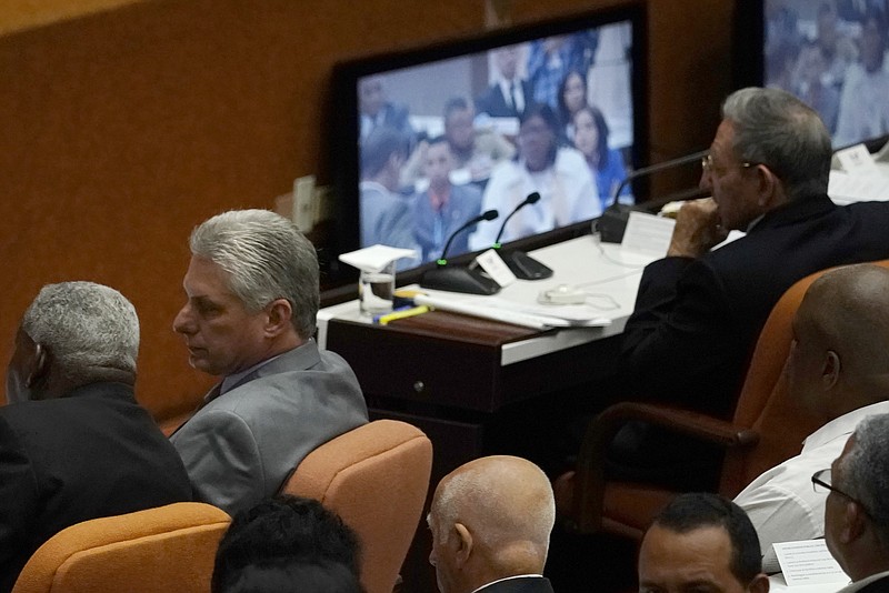 Cuba's President Raul Castro, top right, observes a monitor with he day's proceedings as his expected successor Miguel Diaz-Canel, second left, talks to another person during the start of two-day session of the legislature, in Havana, Cuba, Wednesday, April 18, 2018. Cuba's legislature opened the two-day session that is to elect a successor to President Castro. (AP Photo/Ramon Espinosa)