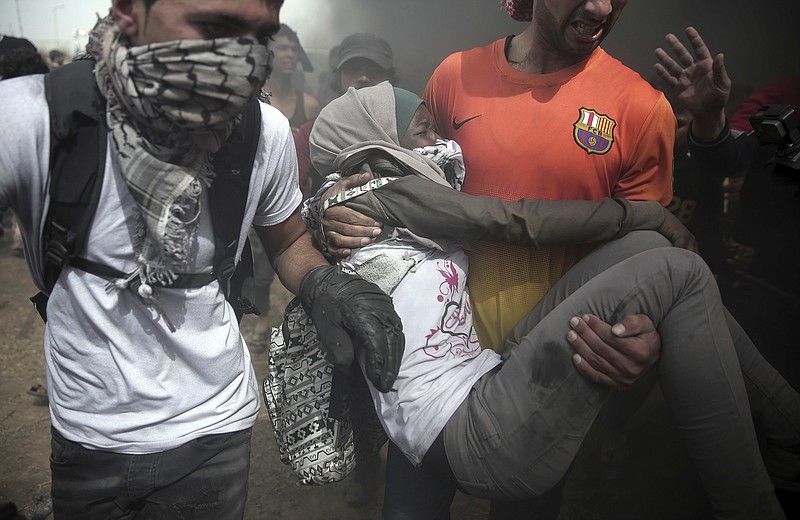 Palestinian protesters evacuate a wounded woman during a protest at the Gaza Strip's border with Israel, Friday, April 20, 2018. Thousands of Palestinians joined the fourth weekly protest on Gaza's border with Israel on Friday, some burning tires or flying kites with flaming rags dangling from their tails. Two Palestinians were killed by Israeli troops firing from across the border fence, health officials said. (AP Photo/ Khalil Hamra)