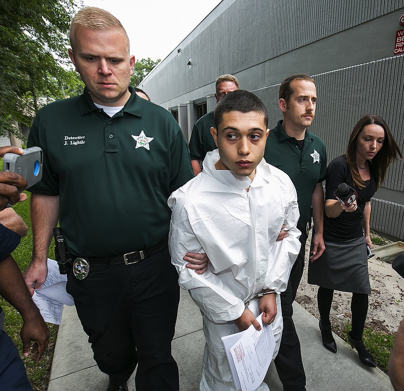 
              Marion County Sheriff's Detectives John Lightle, left, and Dan Pinder, right, escort a handcuffed and shackled Sky Bouche, 19, center, to a waiting patrol car, Friday, April 20, 2018, in Ocala, Fla. Bouche is the suspect in a shooting that occurred at Forest High School Friday morning. (Doug Engle/Ocala Star-Banner via AP)
            