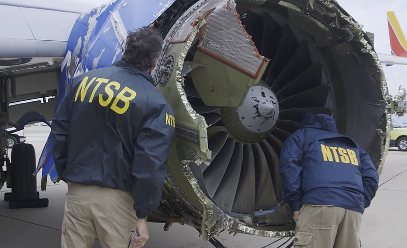 In this Tuesday, April 17, 2018 frame from video, a National Transportation Safety Board investigator examines damage to the engine of the Southwest Airlines plane that made an emergency landing at Philadelphia International Airport in Philadelphia. 