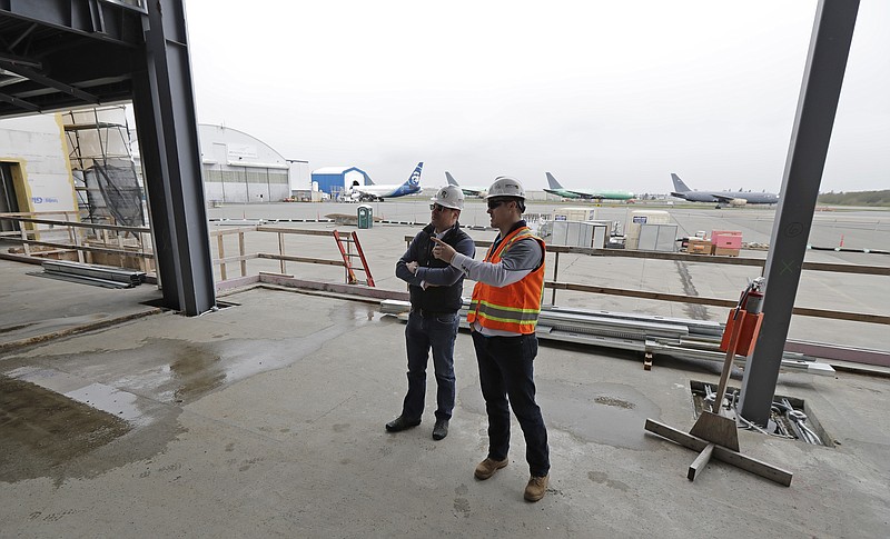 
              In this April 11, 2018 photo, Brett Smith, CEO of Propeller Airports, left, talks with project engineer Todd Raynes, right, inside the privately-run commercial U.S. airport terminal Smith's company is building at Paine Field in Everett, Wash. Propeller Airports sold $50 million in bonds earlier this year to finance the construction, according to data obtained by The Associated Press. The terminal has commitments from Alaska Airlines, Southwest Airlines and United Airlines for up to 24 daily flights, mostly to destinations in the West and Midwest. (AP Photo/Ted S. Warren)
            