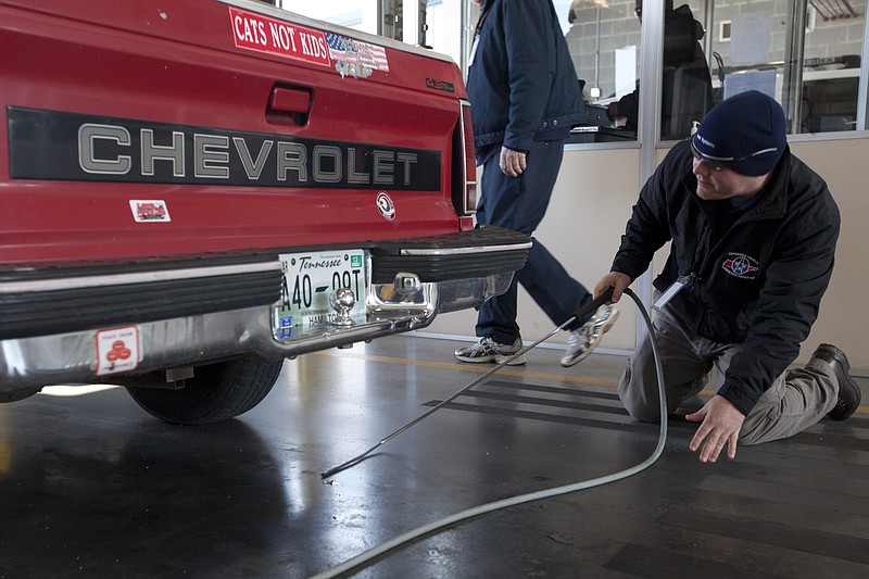 In this Feb. 27, 2013, staff file photo, emissions tester Mark Johnson searches for a tailpipe on a Chevrolet S10 truck at the vehicle emissions testing facility on Riverfront Parkway in Chattanooga, Tenn.