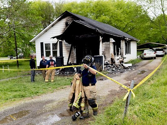 An Alcoa firefighter walks beneath police tape at the scene of an overnight house fire at 885 Wright Road in Alcoa, Tenn., on Sunday, April 22, 2018. (Photo: Calvin Mattheis/Knoxville News Sentinel)