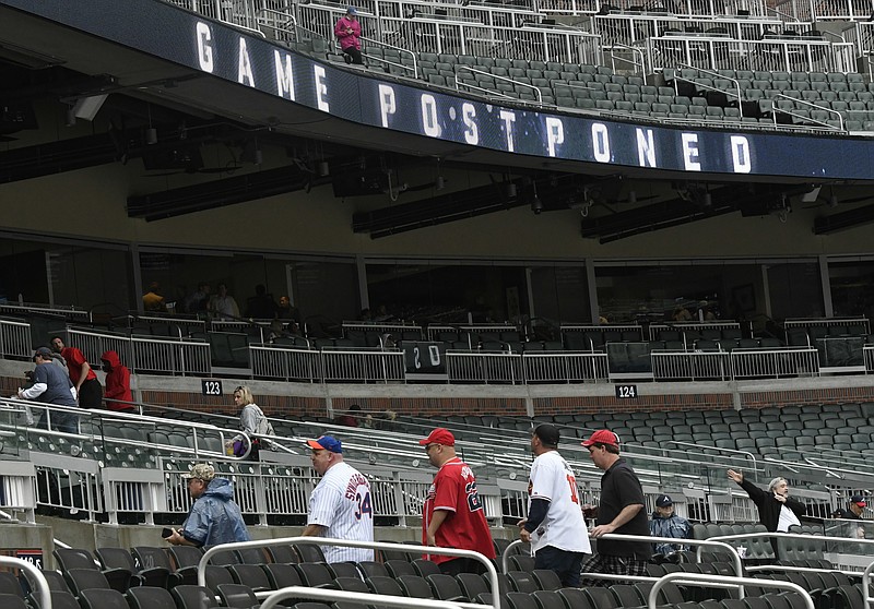 Fans leave after a baseball game between the Atlanta Braves and the New York Mets was postponed due to rain Sunday, April 22, 2018, in Atlanta. (AP Photo/John Amis)