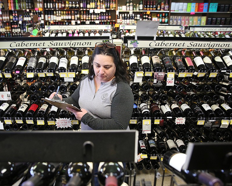 Lori Sharp, owner of Bacchus Wine and Spirits, looks through wine inventory at Bacchus Wine and Spirits on Thursday, Jan. 25, 2018, in Hixson, Tenn.