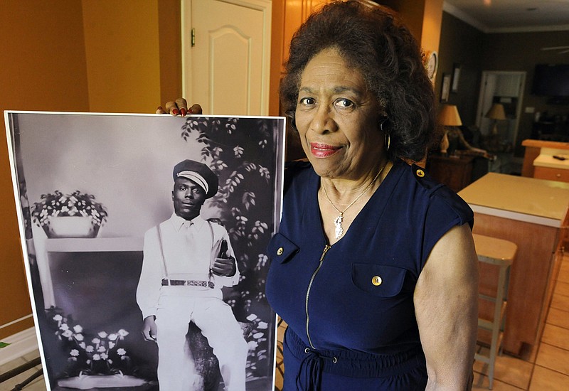 In this Wednesday, April 18, 2018 photo, Josephine Bolling McCall poses with a photo of her father, lynching victim Elmore Bolling, at her home in Montgomery, Ala. Bolling is among thousands of lynching victims remembered at the new National Memorial for Peace and Justice, erected with donations by the Alabama-based Equal Justice Initiative. The memorial and an accompanying museum, which aim to tell the story of racial oppression in the United States, open April 26. (AP Photo/Jay Reeves)