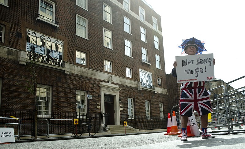 In this Friday, April 24, 2015 file photo, Terry Hutt poses for the media with a sign that reads 'Not Long to Go' as he waits with other royal fans, outside the Lindo wing at St Mary's Hospital in London. Kensington Palace says Prince William's wife, the Duchess of Cambridge has entered a London hospital to give birth to the couple's third child. The former Kate Middleton traveled by car on Monday, April 23, 2018 to the private Lindo Wing of St. Mary's Hospital in central London. The palace says she was in "the early stages of labor." (AP Photo/Alastair Grant, File)