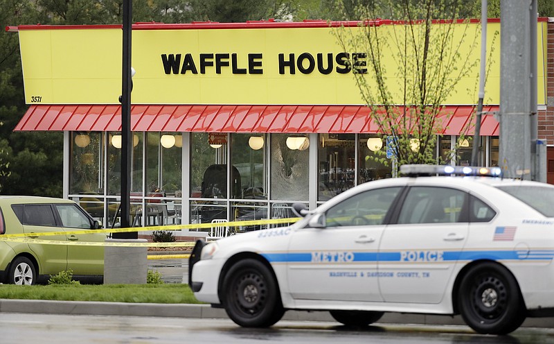 A police car sits in front of a Waffle House restaurant Sunday, April 22, 2018, in Nashville, Tenn. At least four people died after a gunman opened fire at the restaurant early Sunday. (AP Photo/Mark Humphrey)