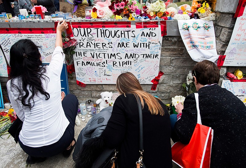People read and pay tribute at a memorial along Yonge Street, Tuesday, April 24, 2018, in Toronto, the day after a driver drove a van down sidewalks, striking and killing numerous pedestrians in his path. (Nathan Denette/The Canadian Press via AP)

