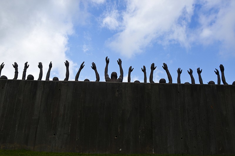 This photo shows a bronze statue called "Raise Up" as part of the display at the National Memorial for Peace and Justice, a new memorial to honor thousands of people killed in racist lynchings, Monday, April 23, 2018, in Montgomery, Ala. The national memorial aims to teach about America's past in hope of promoting understanding and healing. It's scheduled to open on Thursday. (AP Photo/Brynn Anderson)