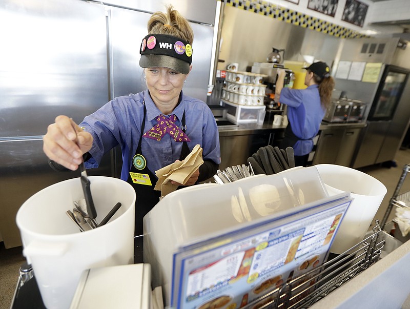 Waffle House employee Krista West replaces silverware Wednesday, April 25, 2018, in Nashville, Tenn. The restaurant re-opened Wednesday after four people were killed by a gunman Sunday. (AP Photo/Mark Humphrey)