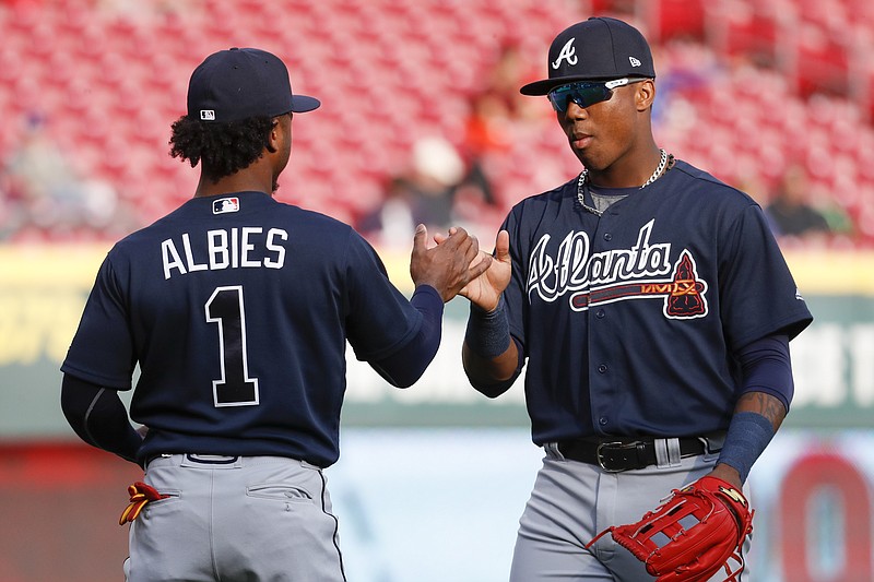 Atlanta Braves center fielder Ronald Acuna Jr., right, and second baseman Ozzie Albies (1) meet on the field as the Braves warmed up for a baseball game against the Cincinnati Reds, Wednesday, April 25, 2018, in Cincinnati. (AP Photo/John Minchillo)