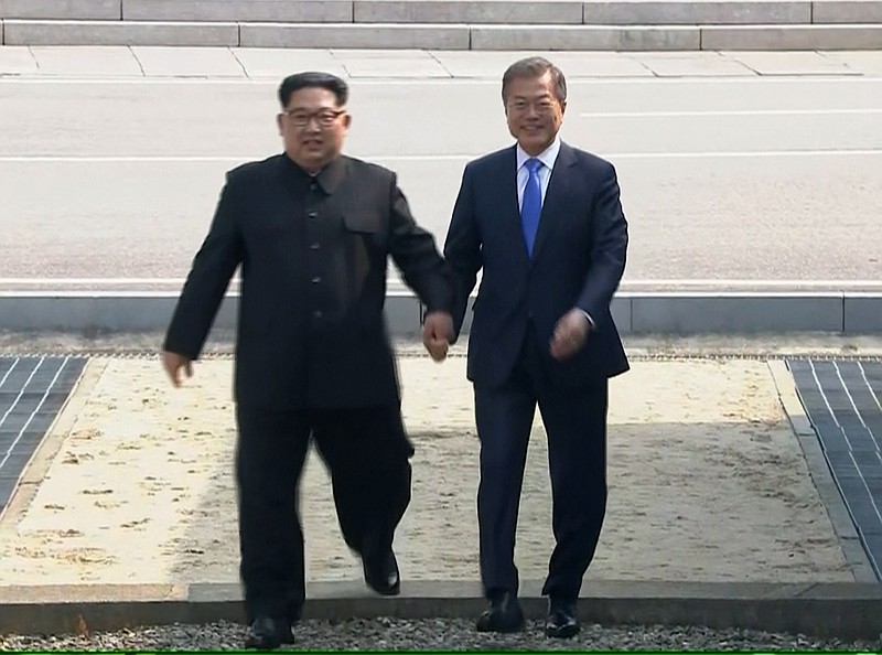 In this image taken from video provided by Korea Broadcasting System Friday, April 27, 2018, North Korean leader Kim Jong Un, left, crosses the border into South Korea, along with South Korean President Moon Jae-in for their historic face-to-face talks, in Panmunjom. Their discussions will be expected to focus on whether the North can be persuaded to give up its nuclear bombs.(Korea Broadcasting System via AP)