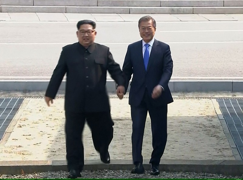 North Korean leader Kim Jong Un, left, and South Korean President Moon Jae-in cross the border into South Korea for historic face-to-face talks in Panmunjom Friday, in an image taken from video provided by Korea Broadcasting System.