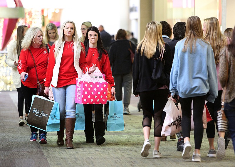 Staff file photo by Erin O. Smith / Samantha Robinson Freemon, Taylor Robinson, and Ralee Robinson, carry bags through Hamilton Place mall as they shopped on Black Friday last November.
