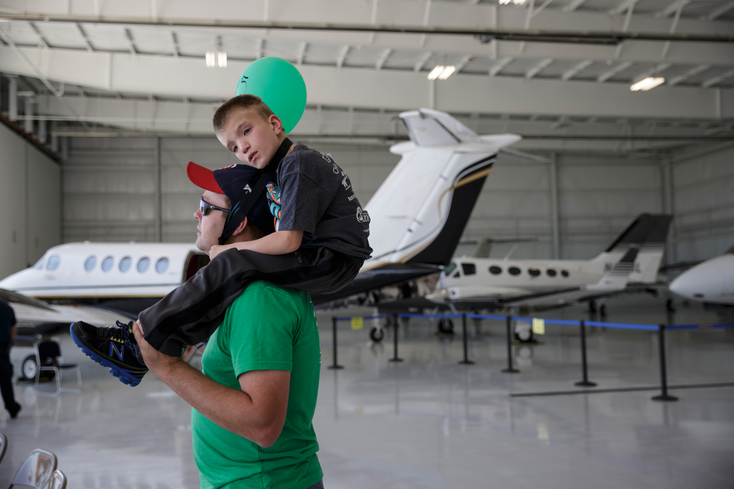 Travis Aalfs rides on his dad Brett's shoulders past aircraft in a hanger during the Challenge Air Fly Day at the Chattanooga Airport's Wilson Air Center on Saturday, April 28, 2018, in Chattanooga, Tenn. Fly Day offers youth ages 7 to 21 with intellectual or physical disabilities and their families the chance to experience a 30-minute small-aircraft flight and to learn about aviation.