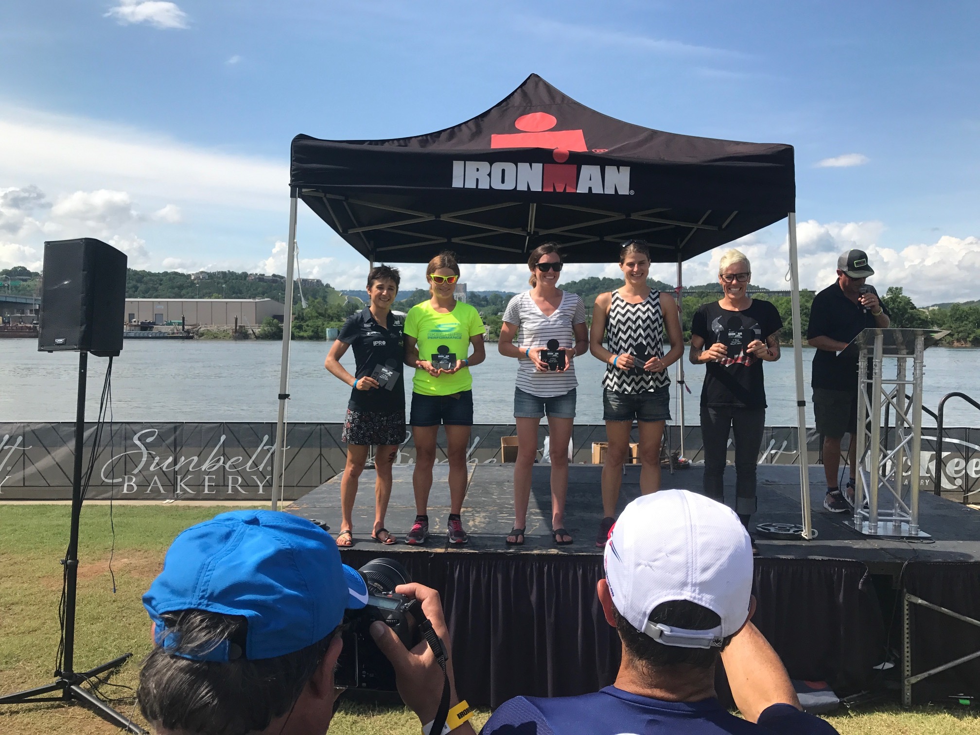 Katie Schumacher snaps a photo as Sarah True, fourth from left, takes the podium. Schumacher hosted True in 2017.