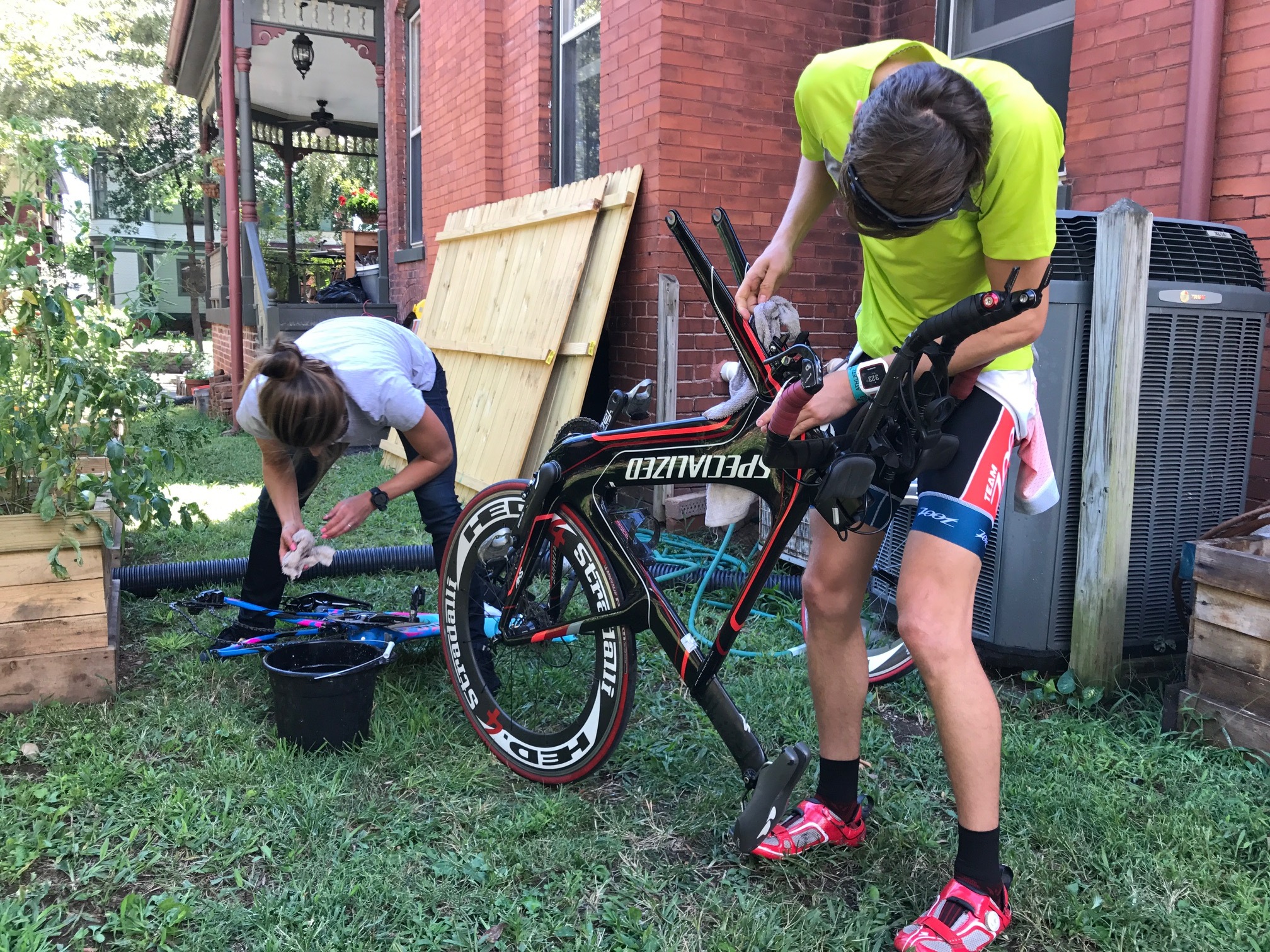 Professional triathlete Sarah True, left, and Katie Schumacher's son Ryan Schumacher clean their bikes together in the Schumachers' backyard.