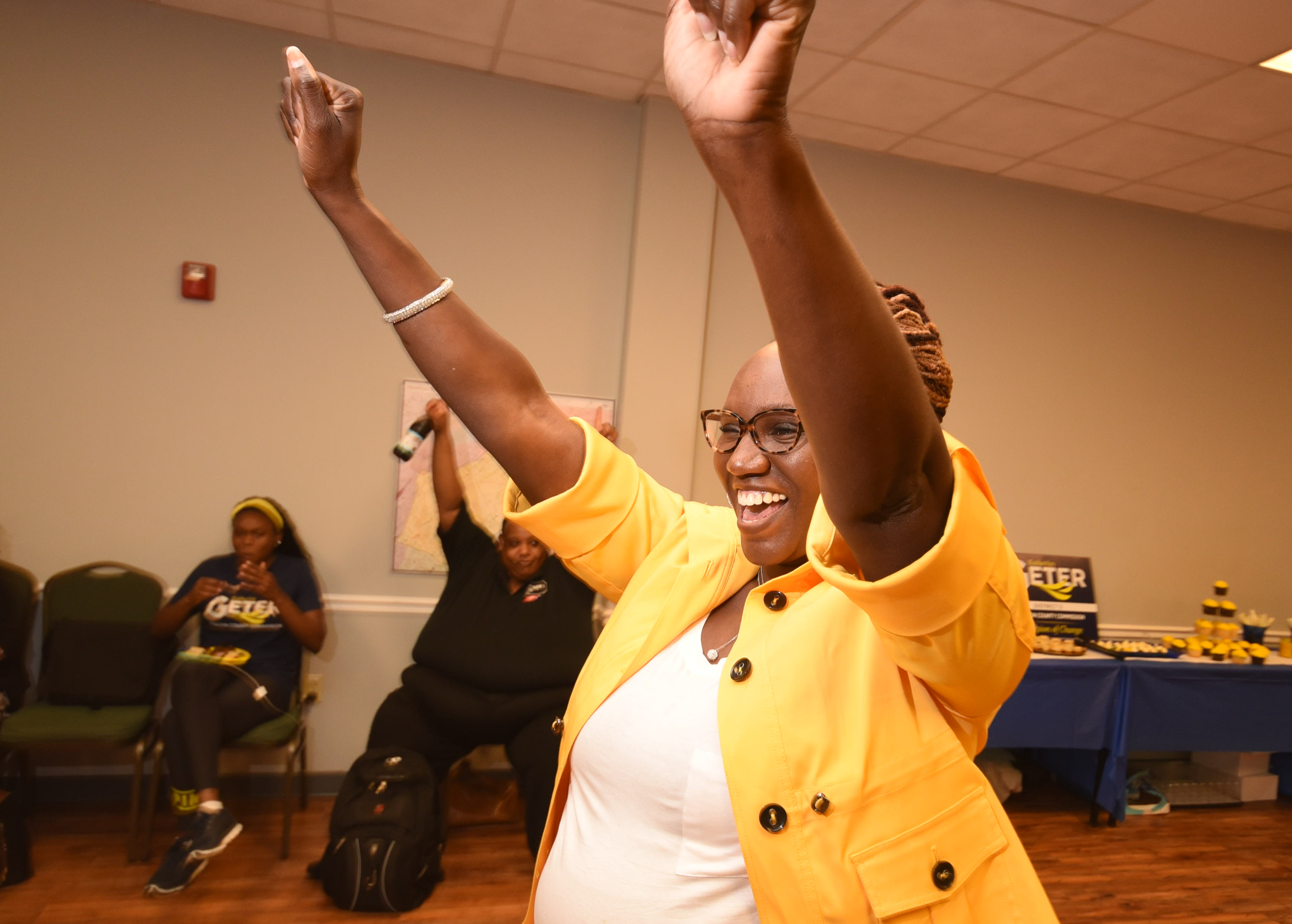 Katherlyn Geter raises her hands in victory after hearing results coming in at Eastgate Town Center Tuesday night.