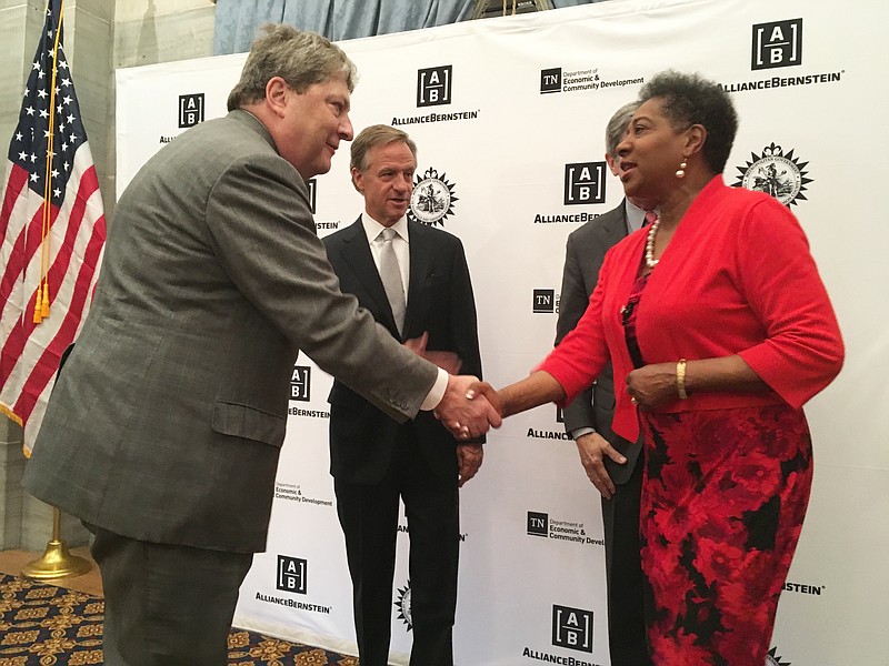 AllianceBernstein LP President and CEO Seth Bernstein, left, shakes hands with state Rep. Brenda Gilmore as Tennessee Gov. Bill Haslam  looks on Wednesday, May 2, 2018, at the state Capitol in Nashville. The financial company announced it will move its global headquarters from New York to Nashville, Tenn., bringing 1,050 jobs and investing more than $70 million in the booming southern city. (AP Photo/Jonathan Mattise)