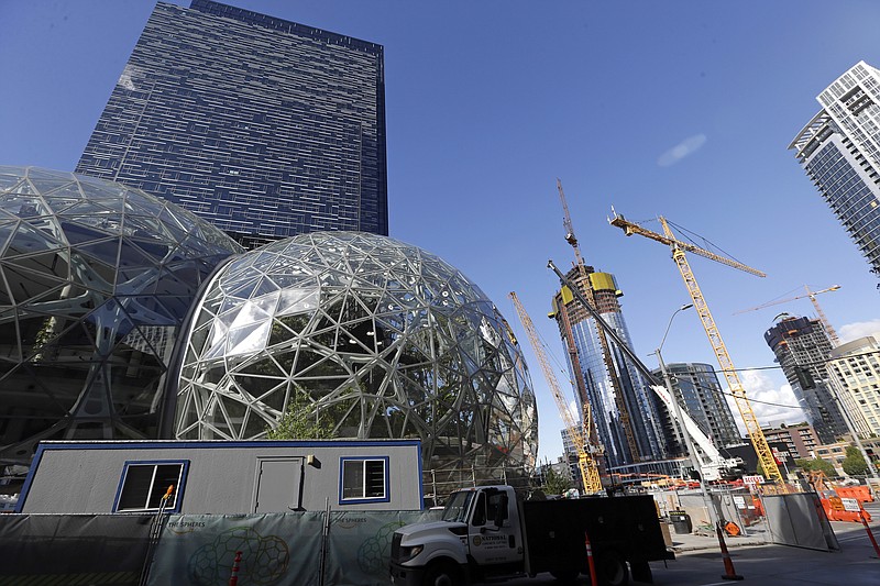 In this Wednesday, Oct. 11, 2017, file photo, large spheres take shape in front of an existing Amazon building, behind, as new construction continues across the street in Seattle. Amazon said Wednesday, May 2, 2018, it is pausing construction on a new high-rise building in Seattle while it awaits the outcome of a city proposal to tax worker hours. The Seattle City Council has been weighing a proposed "head tax" on high-grossing businesses as a way to raise about $75 million a year for affordable housing and homelessness services. (AP Photo/Elaine Thompson, File)