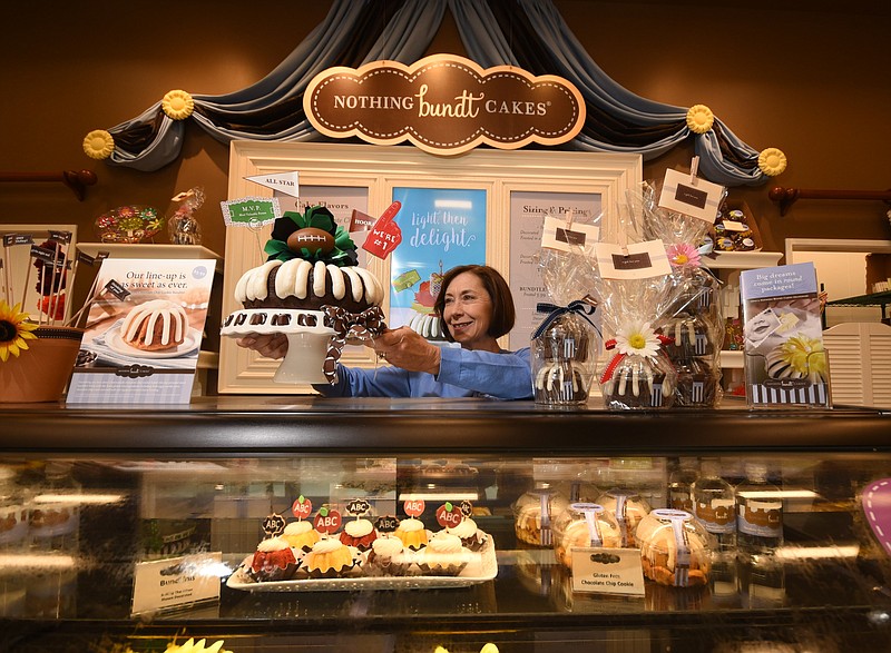 Melinda Mason, owner and operator of Nothing Bundt Cakes, displays an M.V.P.-decorated "Chocolate Chocolate Chip" Bundt cake at her store near Hamilton Place mall.