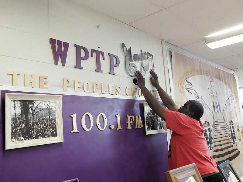Terry Neal, program director for WPTP-FM 100.1, decorates a wall inside the studios at the Chattanooga Civic Center at Mountainside. The Alton Park Development Corp. launched the station on March 8.