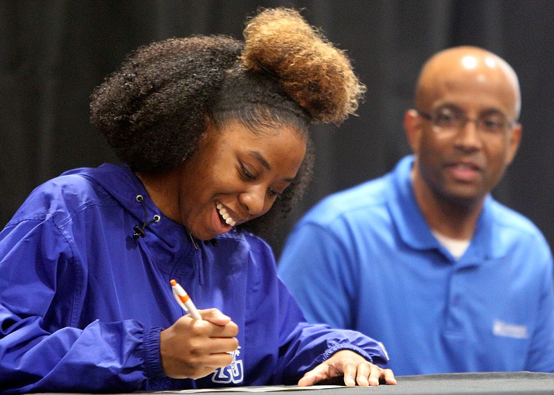 Lacara Bell signs a certificate stating she will be attending Tennessee State University as Tennessee State assistant director of admissions David Harris looks on during the Chattanooga Girls Leadership Academy's College Signing Day event Thursday, May 3, 2018 in the gym at CGLA in Chattanooga, Tenn. Bell plans to major in biology. 