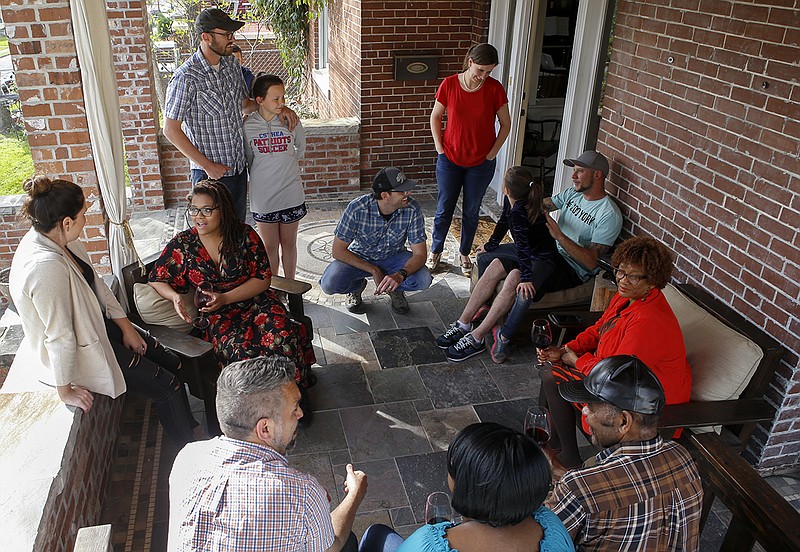 Highland Park neighbors enjoy each other's company on the front porch at the home of Christopher Gehrke, picture crouching in the middle. Also pictured is Emerson Burch at bottom left.