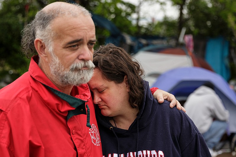 Keim Shirley, left, puts his arm around Tracy Corello in a homeless encampment behind the city's wellness center on East 11th Street on Friday, April 6, 2018, in Chattanooga, Tenn. City service coordinators were on site at the camp Friday to help residents find temporary housing, because the camp is located on a toxic brownfield. 