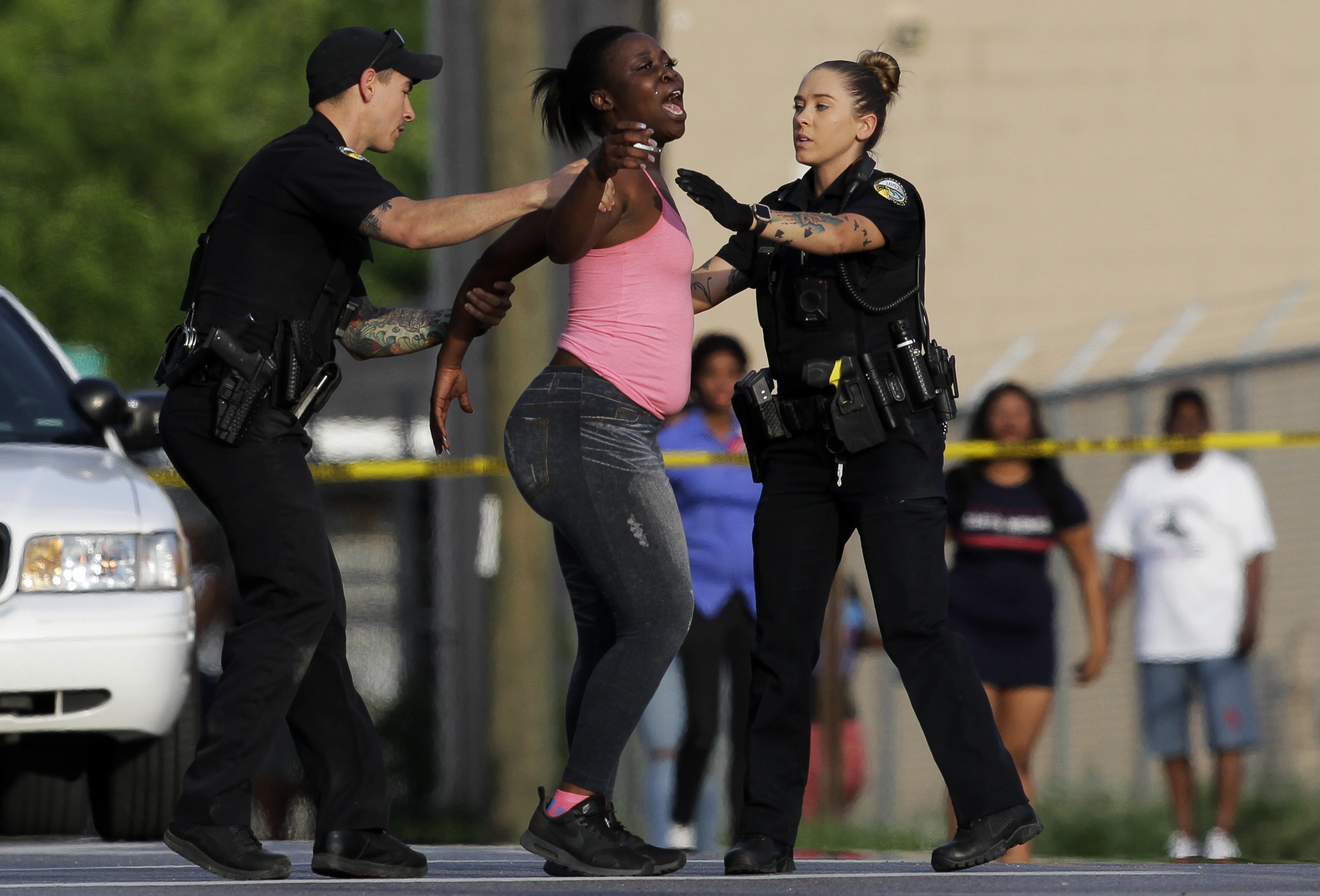 Two police officers try to comfort a woman and move her behind the police tape at the scene of a fatal shooting at the intersection of Central Avenue and West 38th Street on Sunday, May 6, 2018 in Chattanooga, Tenn.