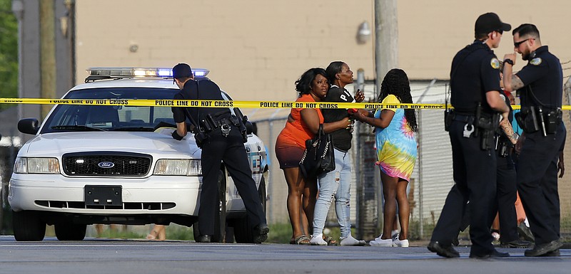 Two women try to comfort a third woman as police work the scene of a fatal shooting at the intersection of Central Avenue and West 38th Street on Sunday, May 6, 2018 in Chattanooga, Tenn.