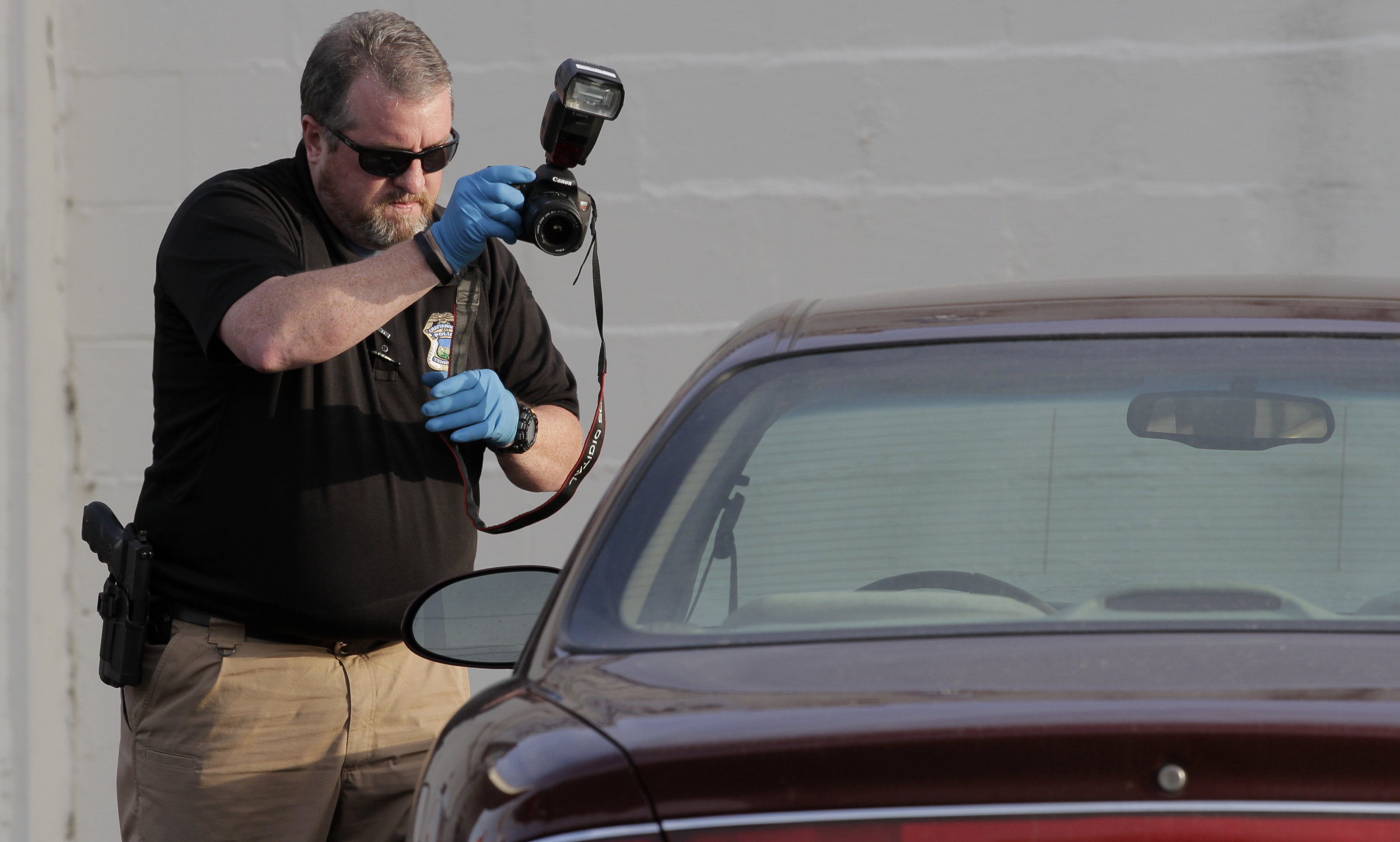 A police officer photographs a car outside of the Nine Brothers convenience store, at the intersection of Central Avenue and West 38th Street, on Sunday, May 6, 2018 in Chattanooga, Tenn.