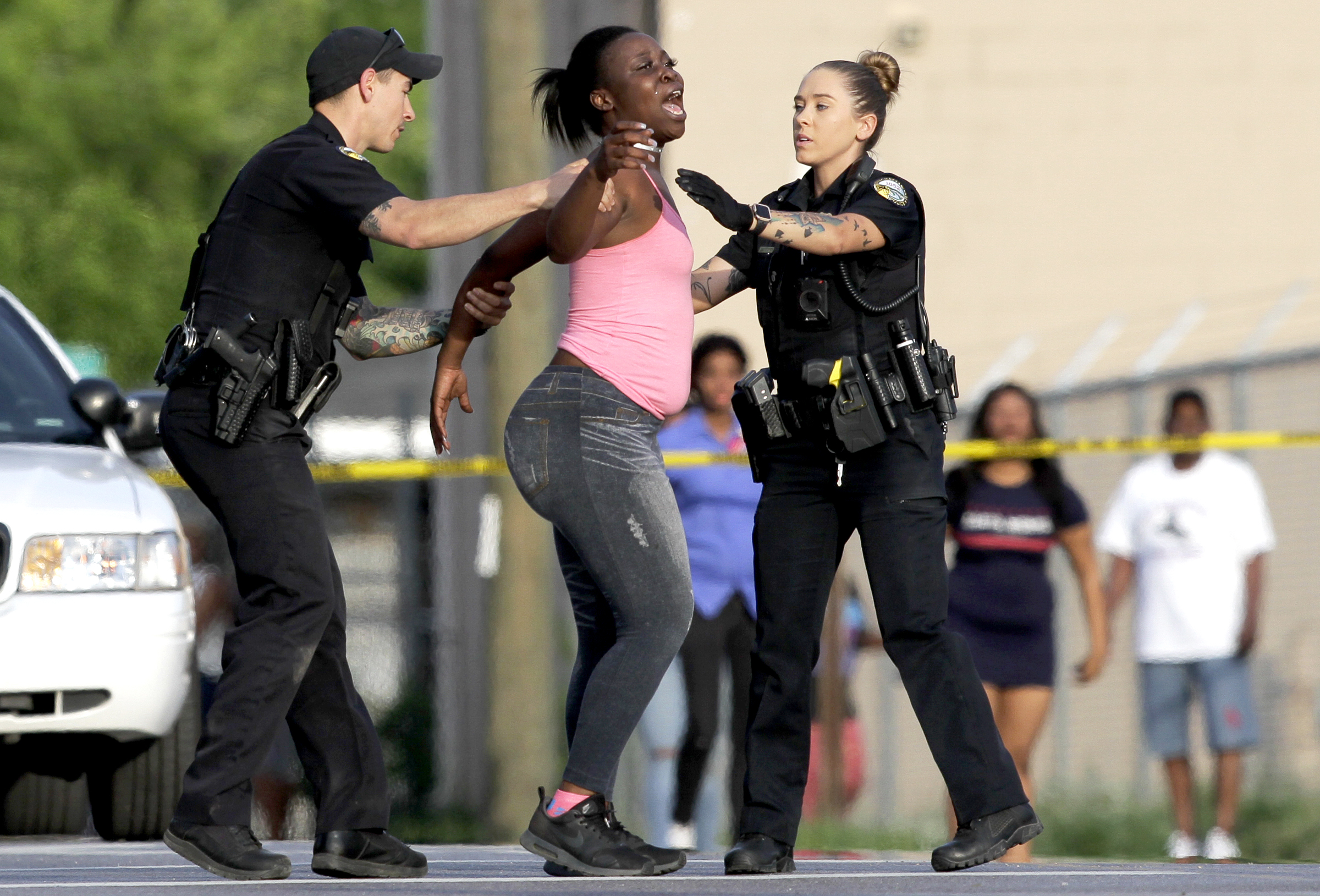 Two police officers try to comfort a woman and move her behind the police tape at the scene of a fatal shooting at the intersection of Central Avenue and West 38th Street on Sunday, May 6, 2018 in Chattanooga, Tenn.