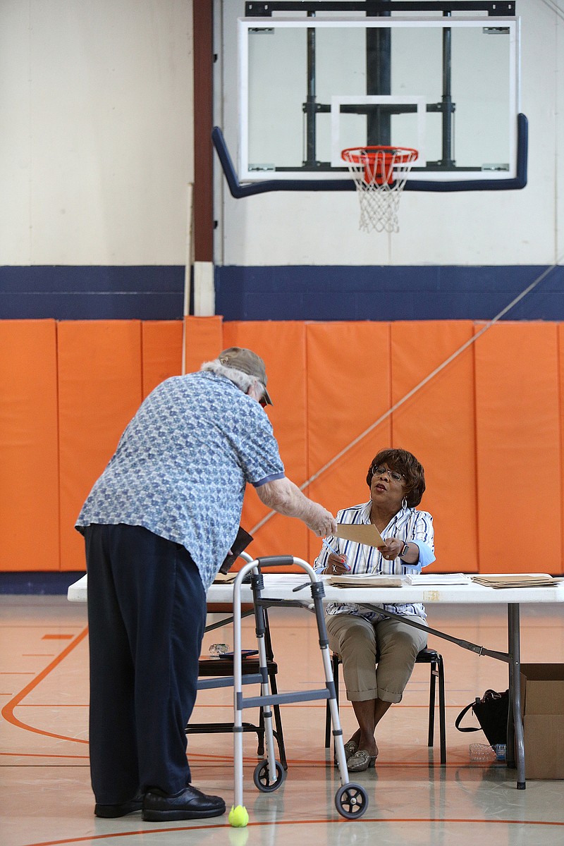 Leaning on his walker, Fred Branum takes a voting ballot from Eleanor Graves during May 1 primary elections in the gym at East Ridge City Hall. A public meeting is set for May 20 at Chattanooga State on the issue of access to voting by people with disabilities.

