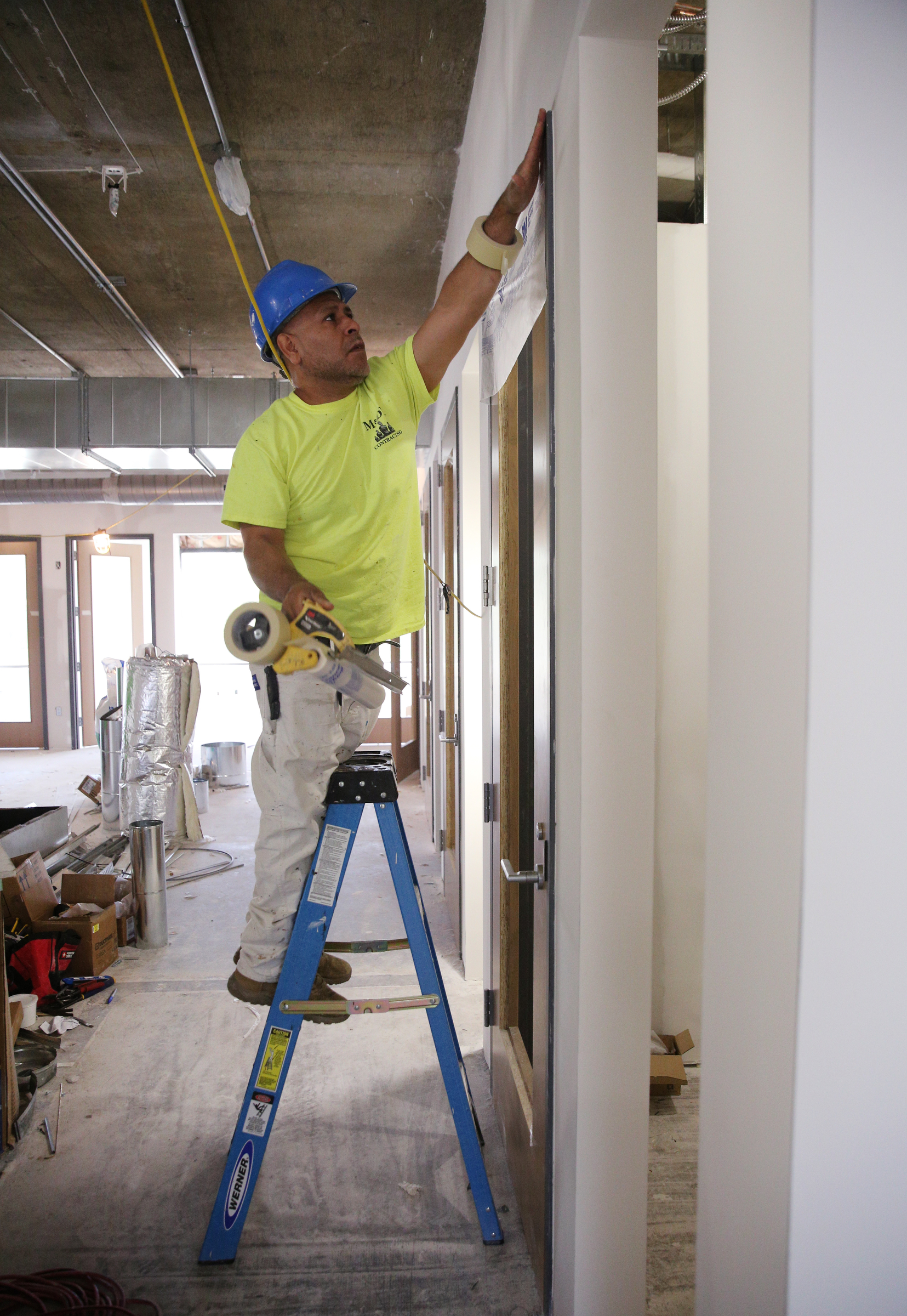 Jose Cisneros, a painter with M&DK Contracting, puts up plastic sheets around doorways in E/SPACES Wednesday, May 2, 2018 in Chattanooga, Tenn. The facility in Chattanooga will be their third location with the other two being in Franklin, Tenn., and Nashville, Tenn.