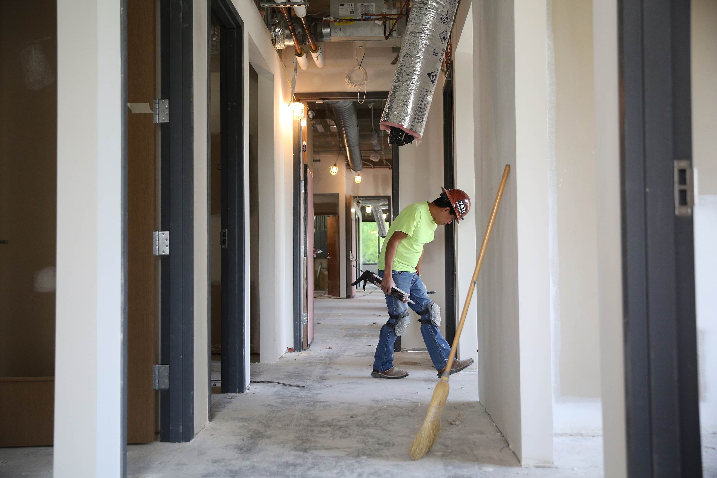 Amarcos Perez with Commercial Drywall Inc. looks around the bases of offices in E/SPACES to determine where he need to add caulking Wednesday, May 2, 2018 in Chattanooga, Tenn. Perez and others in his crew were cleaning up drywall remnants from the floor and caulking gaps between the walls and flooring of the work being done on the second floor of University Tower.