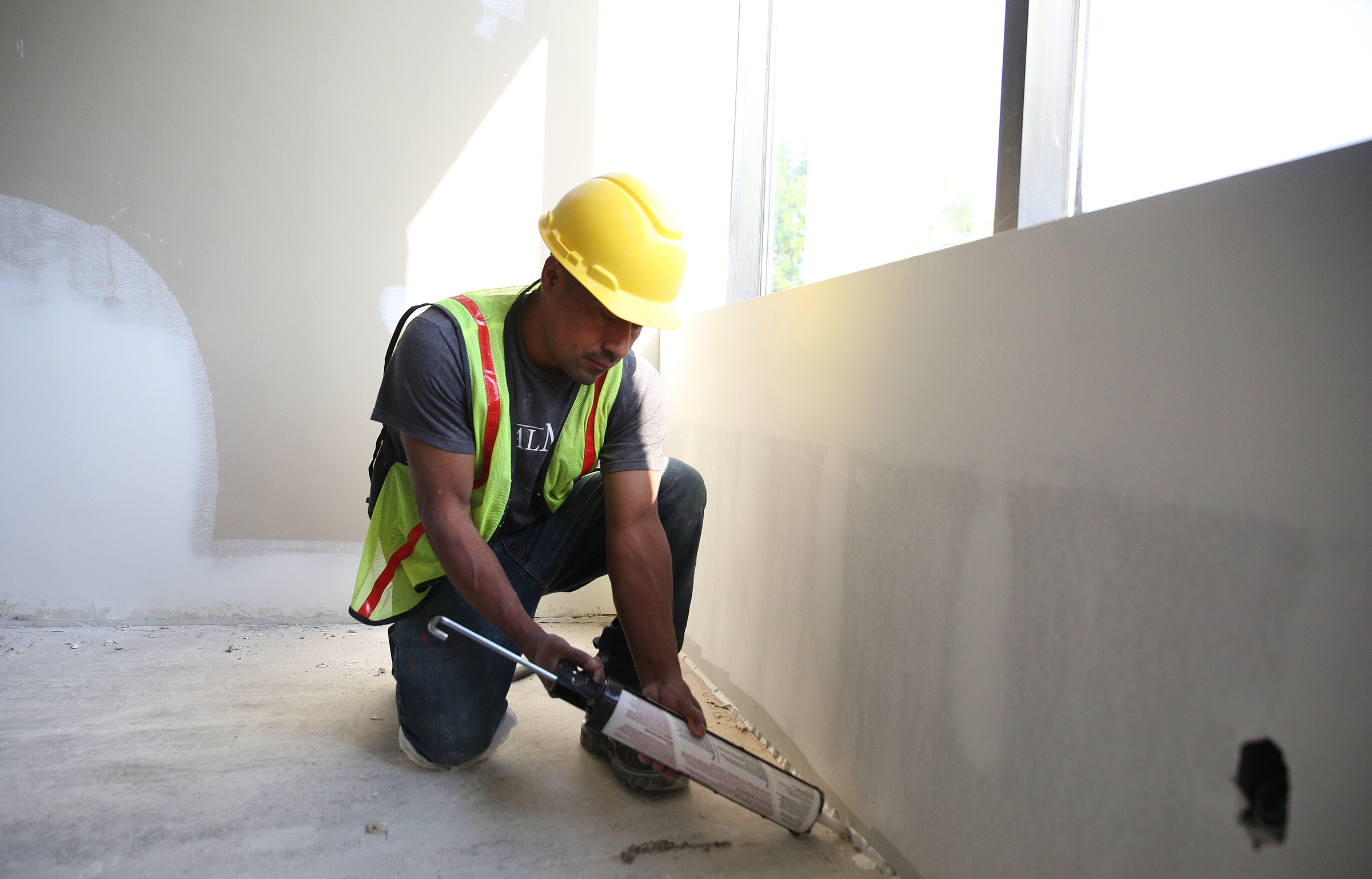 Ruben Lopez with Commercial Drywall Inc. adds caulking in the gaps between the walls and floor at E/SPACES Wednesday, May 2, 2018 in Chattanooga, Tenn. E/SPACES offers a variety of offices as well as meeting rooms and larger common spaces.
