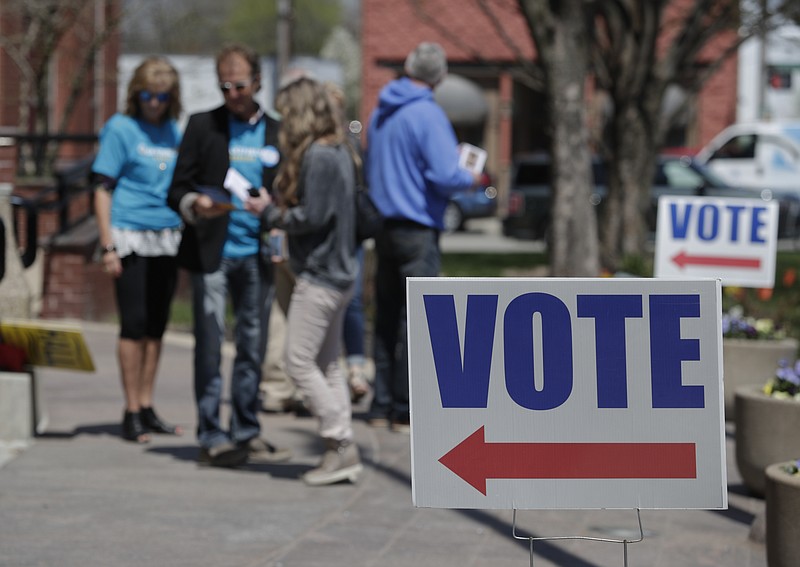 Electioneers greet voters during in Noblesville, Ind. (AP Photo/Michael Conroy)