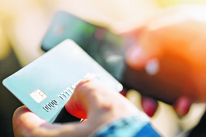 A man uses a mobile phone to pay for utilities. Concepts of using mobile technologies and smarfon in mobile applications in the online business for payment with a credit card remotely