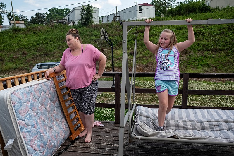 Tonya Evans, left, stands on the porch of her family's trailer in the Stoney Pointe Mobile Home Park as her daughter Sheridan plays on a porch swing on Wednesday, May 9, 2018, in Rossville, Ga. Tonya and Brian Evans say they purchased their trailer from Tom Lackey, the owner of the mobile home park, only to later discover that Lackey never owned the trailer.