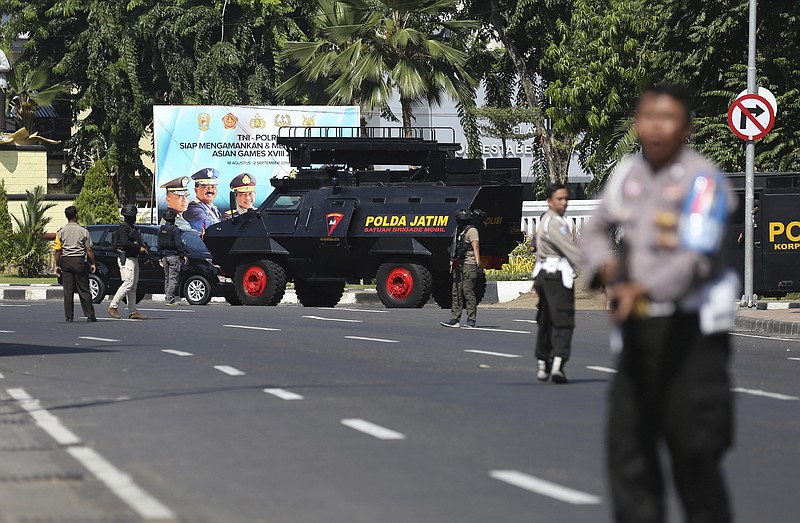 Officers block a road following an attack at the local police headquarters in Surabaya, East Java, Indonesia, Monday, May 14, 2018. The police headquarters in Indonesia's second largest city was attacked Monday by suspected militants who detonated explosives from a motorcycle, a day after suicide bombings at three churches in the city. (AP Photo/Achmad Ibrahim)
