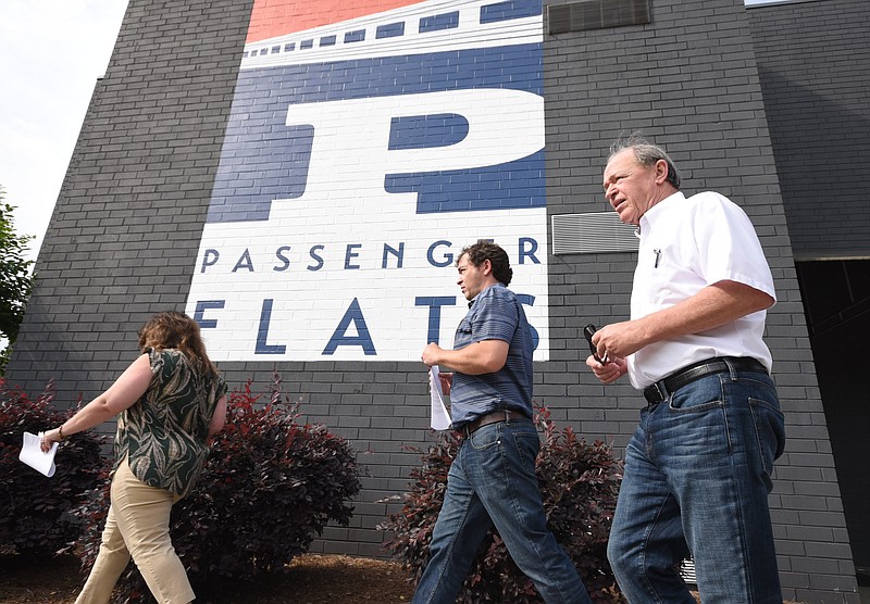 Jon Kinsey, right, Adam Kinsey and apartment manager Cat Collier Martinez walk past the first phase of the Passenger Flats apartments, on their way to the back of the property where another building at the hotel has been converted into apartments at the Chattanooga Choo Choo.