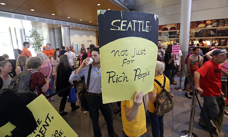 People fill a hallway before a Seattle City Council meeting where the council was expected to vote on a "head tax" Monday, May 14, 2018, in Seattle. The council is to vote on a proposal to tax large businesses such as Amazon and Starbucks to fight homelessness. The plan would tax large businesses about $500 a year per worker to raise about $75 million a year for homeless services and affordable housing. (AP Photo/Elaine Thompson)