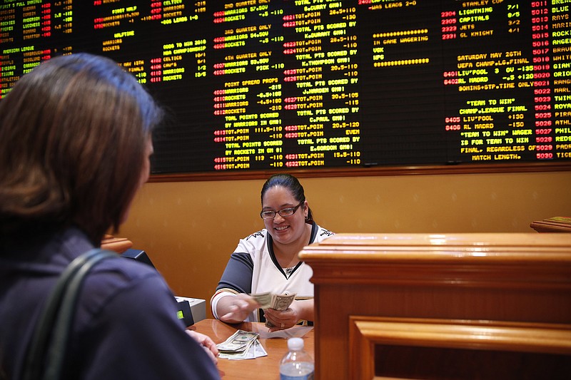 
              Crystal Kalahiki pays out a bet in the sports book at the South Point hotel-casino, Monday, May 14, 2018, in Las Vegas. The Supreme Court on Monday gave its go-ahead for states to allow gambling on sports across the nation, striking down a federal law that barred betting on football, basketball, baseball and other sports in most states. (AP Photo/John Locher)
            