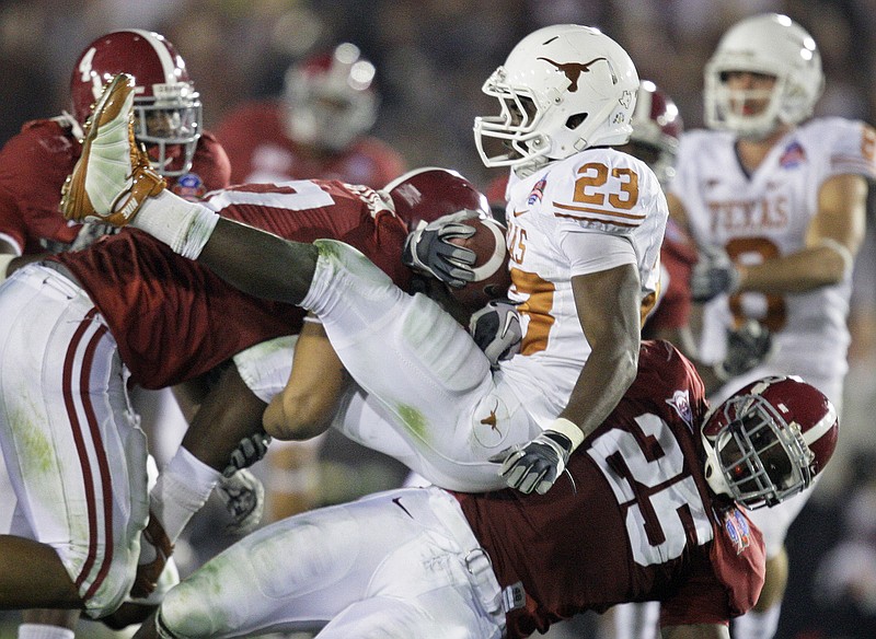Texas running back Tre' Newton (23) is taken down by Alabama linebacker Rolando McClain (25) and defensive lineman Lorenzo Washington during the BCS championship game after the 2009 season. The Longhorns and the Crimson Tide are scheduled to meet in the 2022 and 2023 regular seasons.